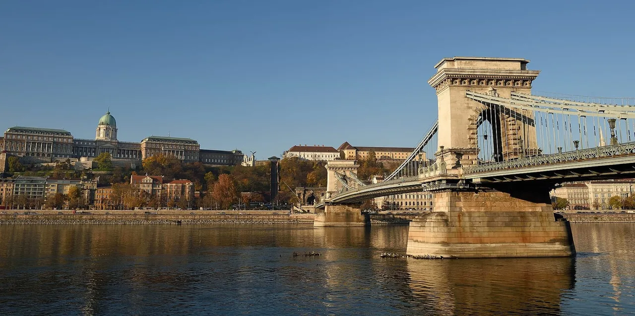Stone pylon of the Széchenyi Chain Bridge over the Danube, with the domed Buda Castle palace on the hill across the river.