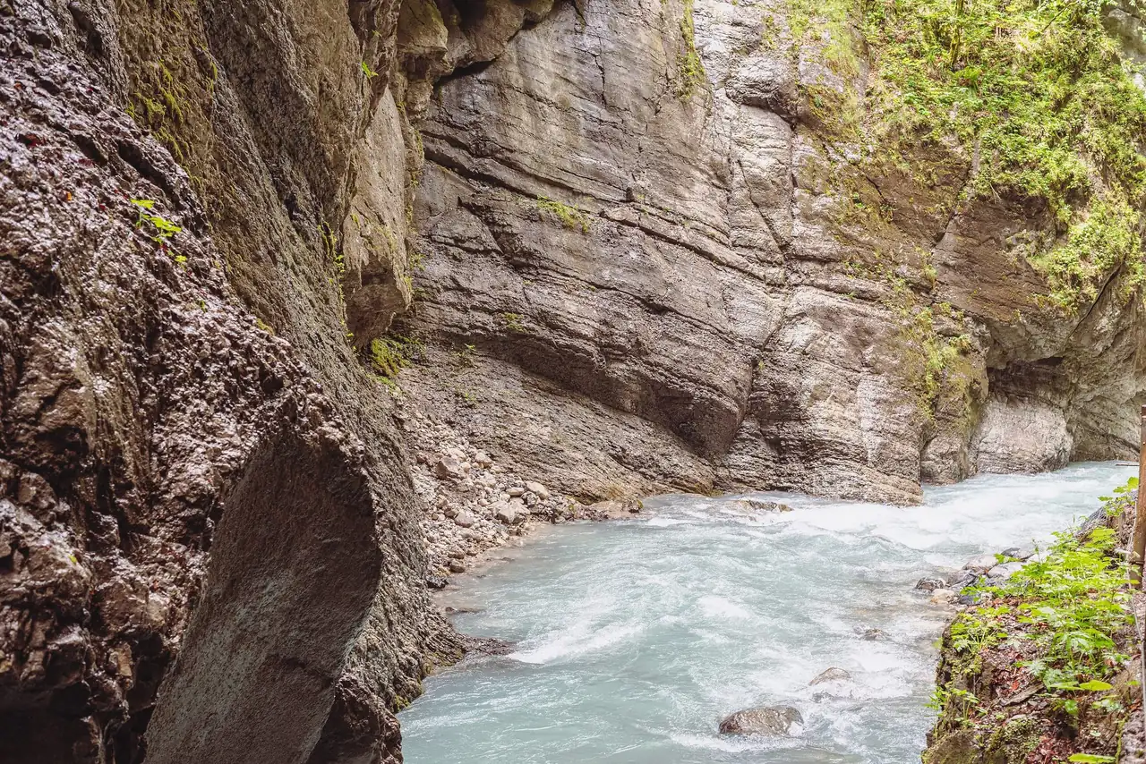 The Partnach river rushing through a narrow gorge between wet limestone walls