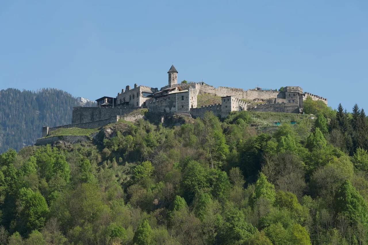 Landskron castle ruin standing on a wooded hill above Villach on a clear day