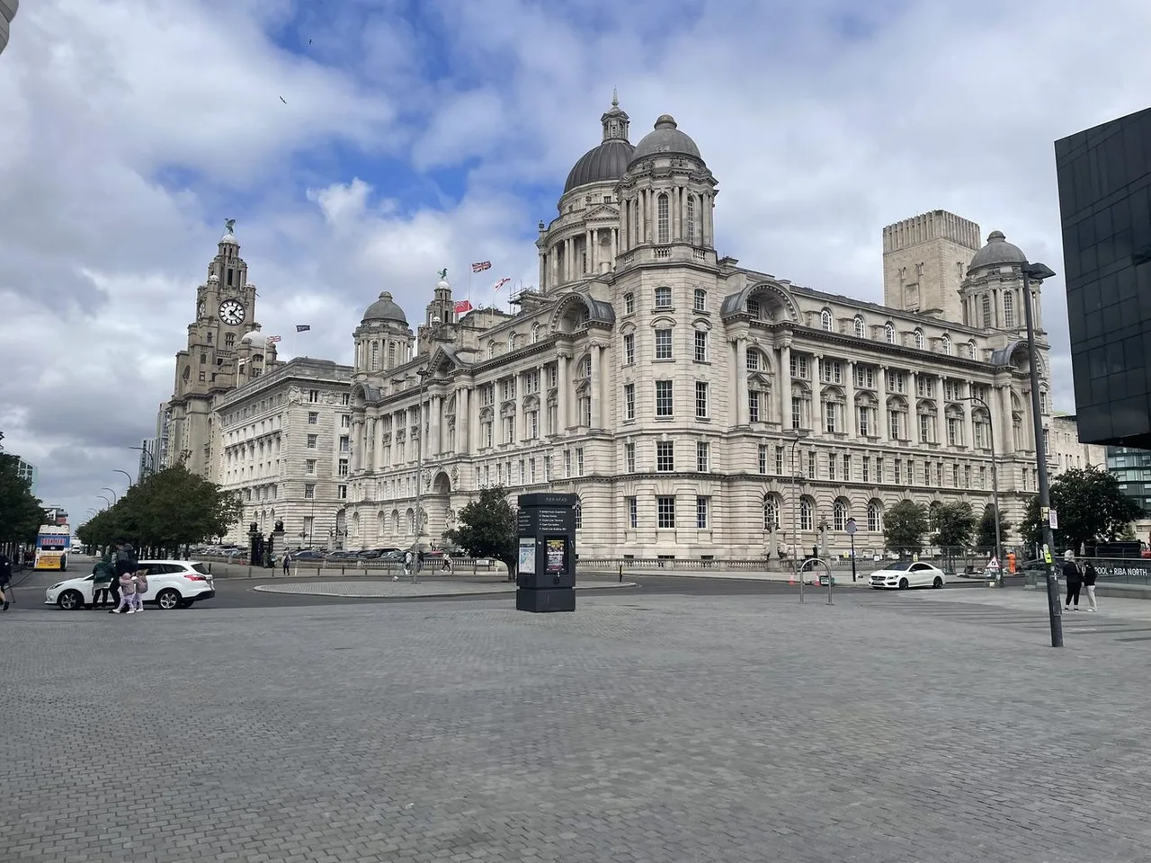 The clock tower of the Royal Liver Building and the domed Port of Liverpool Building beyond a wide cobbled square at the Pier Head.