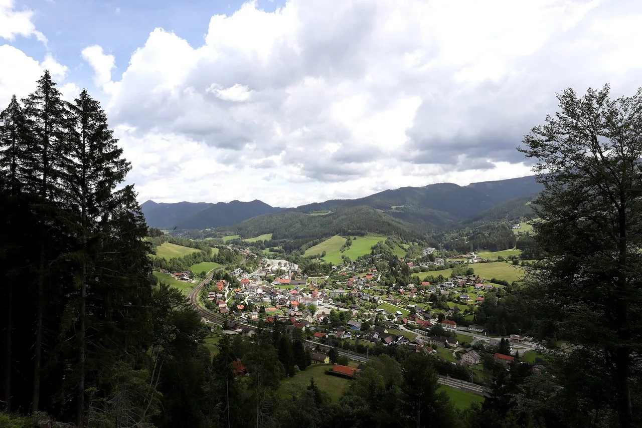Spital am Semmering seen from above through the trees, with the railway line running through the village and wooded hills behind