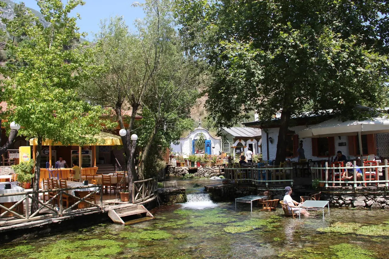 Cafes and restaurants beside the clear, spring-fed Azmak stream in Akyaka, shaded by trees